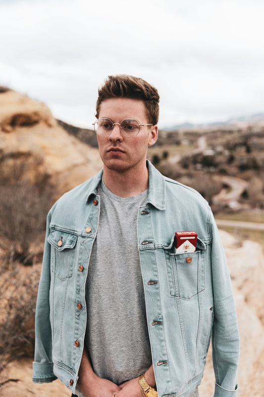 man in blue denim button up jacket wearing black framed eyeglasses