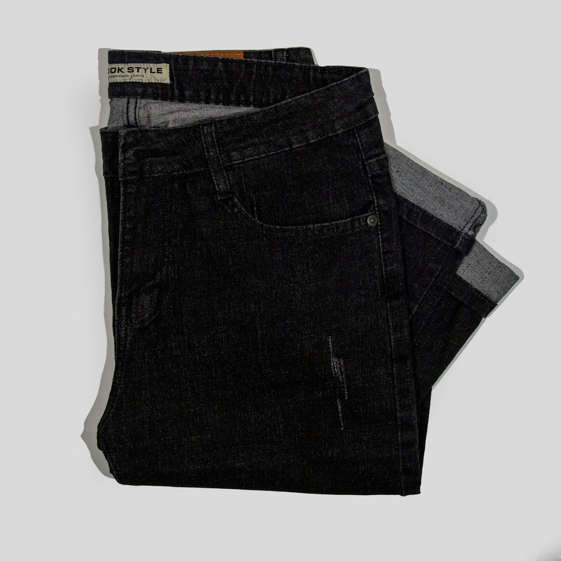 a pair of black jeans sitting on top of a white surface