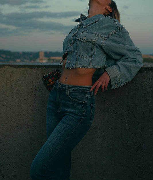Woman poses in denim jacket and jeans.