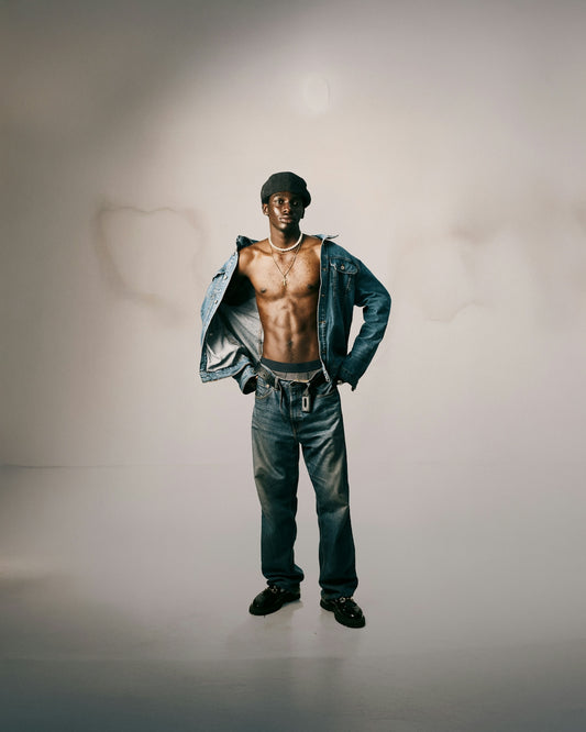 Man wearing denim jacket and jeans with hands on hips