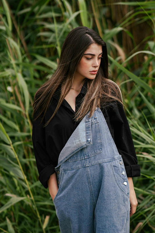 Young woman in denim overalls standing in tall grass