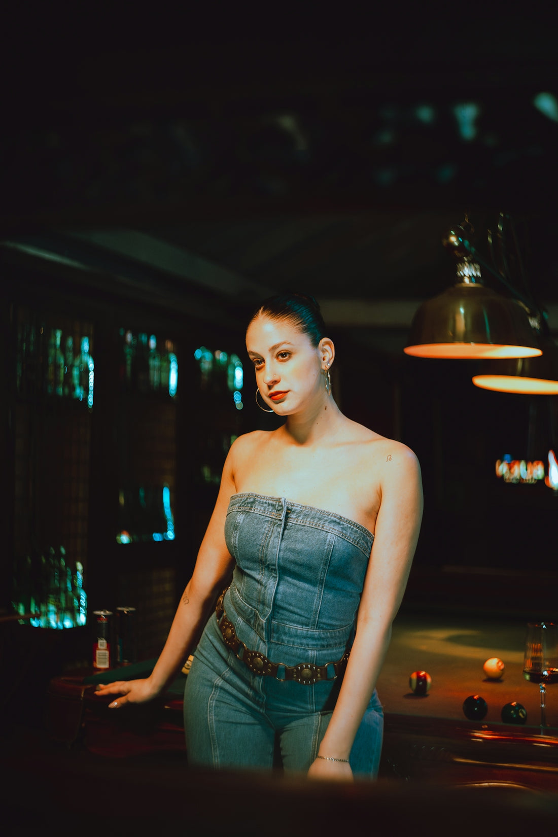 Woman in denim outfit poses by a pool table