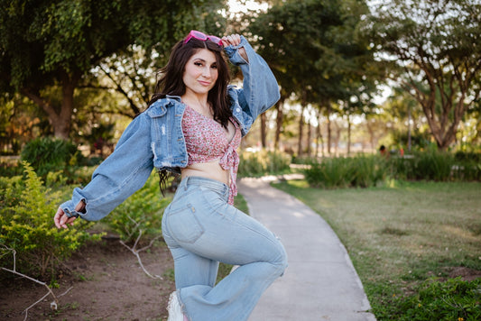 A woman in denim jacket and jeans poses outdoors.
