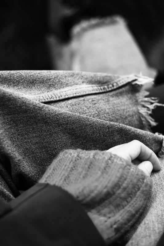 A person's hand resting on denim jeans