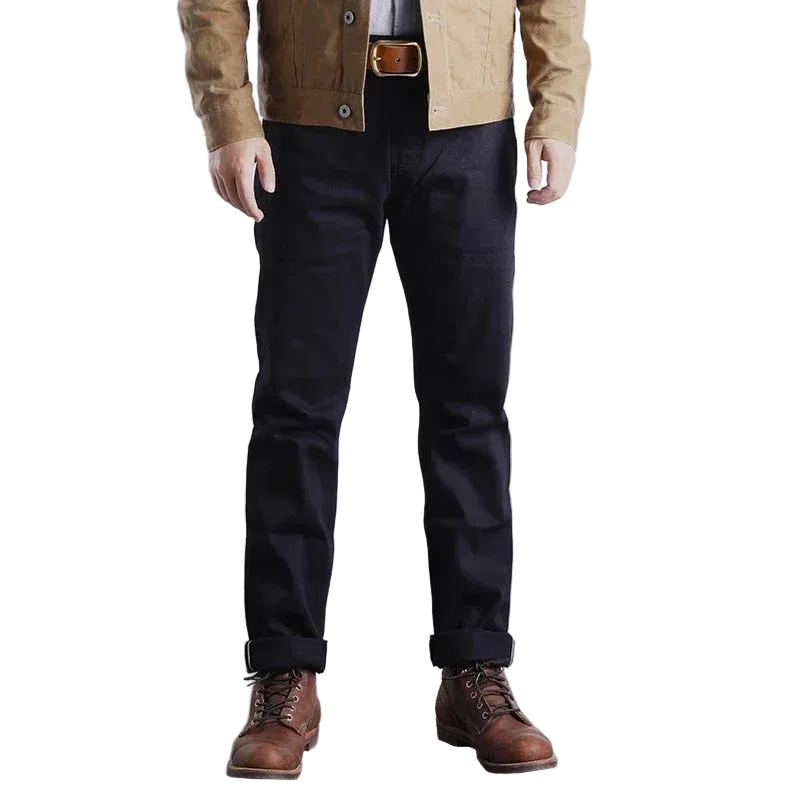 Men's dark blue denim jeans, slim fit, high-quality material, paired with brown boots and a tan jacket.